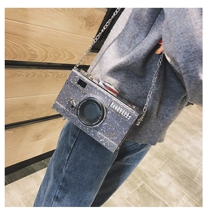 Detail of silver sequin camera-shaped crossbody bag with metallic chain strap and text