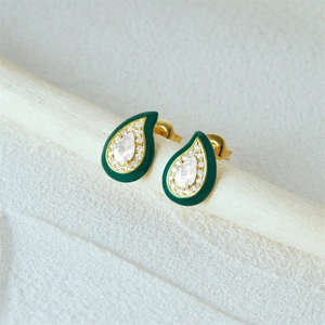 Macro shot of gold teardrop earrings with dark green enamel and sparkling center crystal