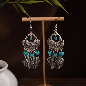 Detail of bohemian silver earrings with blue turquoise beads and leaf charms