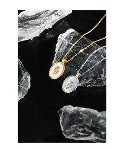 Detail of oval shell necklaces with tulip relief on black mirror with ice props
