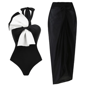 Detail of one-piece swimsuit with large white bow and sheer black beach sarong skirt
