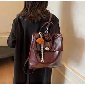 Detail of burgundy glossy leather backpack with silver twist lock and teddy charm