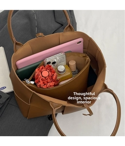 Detail view of woven brown tote bag interior filled with daily items like a tablet