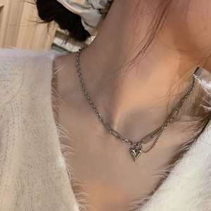 Détail du collier avec pendentif cœur argenté, maillons mixtes et petites franges