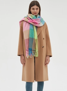 Detailed view of colorful plaid scarf with tassels styled on a camel wool coat