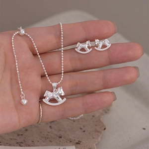 Detailed close-up showing rocking horse pendant and earrings with silver metallic luster