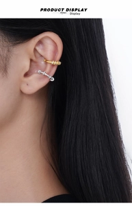 Detail of silver and gold cuff earrings with crystals on a female model's ear