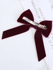 Detail view of burgundy velvet hair bow with gold chain trim and metal spring clip