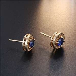 Makro-Detail goldener Halo-Ohrstecker mit dunkelblauem Stein und Zirkonia-Umrandung
