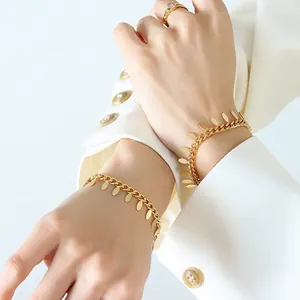 Thai style chunky gold chain bracelet with leaf pendants on model with white blazer