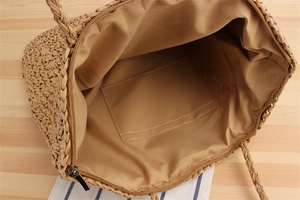 Detail view of woven paper rope bag showing khaki fabric lining and zipper closure