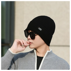 Close-up of black ribbed knit beanie featuring a minimalist woven label for men