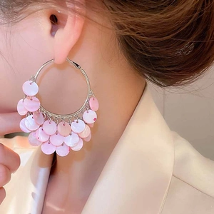 Close-up of pink shell sequin tassel hoop earrings on model for a resort style look