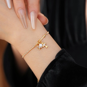 Gros plan d'un bracelet doré croix et perles avec zircons étincelants sur le poignet