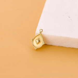Vue macro détaillée d'un pendentif goutte en métal doré avec texture de losange et anneau