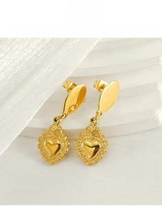 Close-up of golden stainless steel heart earrings with embossed vintage relief patterns
