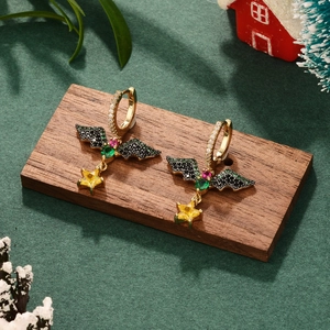 Exquisite Christmas bell earrings with green zircon and tassel on festive background