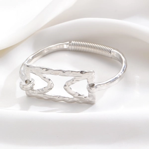 Detail of silver alloy open bangle with hollow geometric motif and hammered metal texture