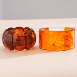 Close-up of acrylic resin bangles with amber tortoiseshell smudge effect and glossy finish