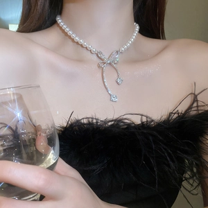 Gros plan du collier de perles avec un pendentif nœud en strass scintillant sur un modèle