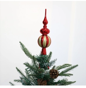 Primo piano del puntale per albero a righe rosse e oro su un ramo di Natale