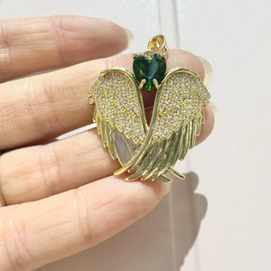 Detail of gold angel wing pendant with green heart stone and zircon micro-pave