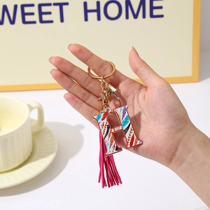 Detail of letter H keychain with ethnic patterns, pink tassel, and gold-tone hardware