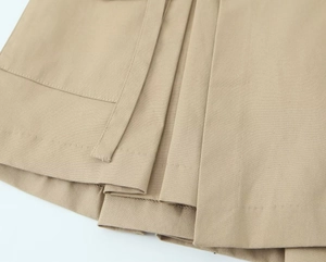 Detailed macro view of khaki cargo skirt-pants showing high-density twill fabric and pleats