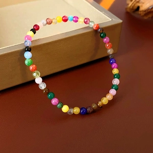 Macro detail of colorful dopamine gemstone beaded bracelet resting on a gold jewelry box