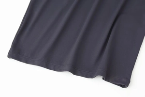 Détail de robe gris foncé montrant des coutures précises et la texture de l'ourlet