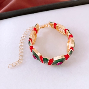 Macro shot of ethnic style gold bracelet with vibrant red beads and green gemstones