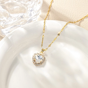 Macro shot of heart-shaped zircon pendant with gold chain on elegant ceramic tray
