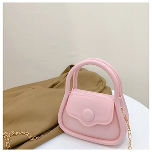 Pink mini jelly bag with golden metal chain strap and top handle in a still life setting