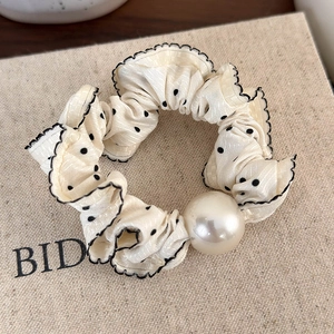 Close-up of vintage polka dot hair scrunchie with ruffle edges and a large pearl