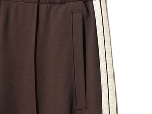 Macro detail of brown tracksuit fabric with white side stripes and hidden zip pocket