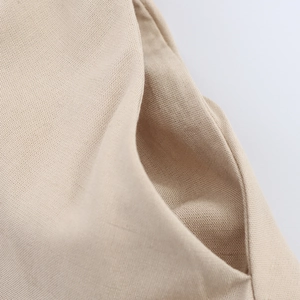 Detaillierte Makroansicht des beigen Leinenmischgewebes und der feinen Nähte am Kleid