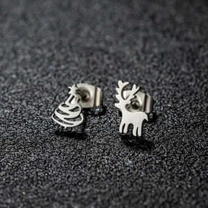 Macro detail of asymmetric Christmas stud earrings featuring a silver reindeer and Xmas tree