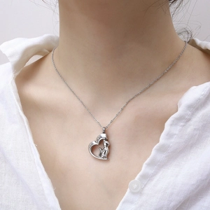 Detail view of heart-shaped silver urn necklace with cat charm worn by a model