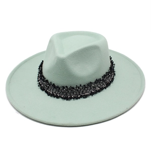 Détail d'un chapeau fedora en laine vert menthe avec ruban décoratif en tweed noir et argent