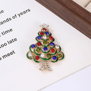 Detail of a gold Christmas tree brooch with colorful rhinestones on a wooden tray