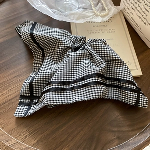 Close-up of black and white plaid hair tie with ribbons on vintage wooden surface