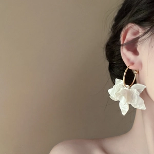 Elegant white floral resin hoop earrings with gold trim worn by a model in profile view