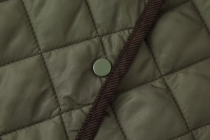 Détail du tissu matelassé vert olive avec bordure en velours et bouton pression
