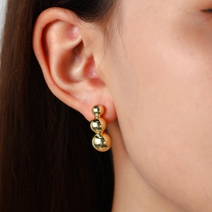 Macro detail of three-tier gold-plated hollow sphere earrings on a model profile