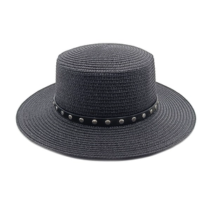 Détail d'un chapeau de paille canotier avec ruban noir orné de rivets métalliques argentés