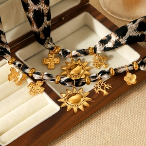Leopard print ribbon necklace with golden sun, butterfly, and cross pendants in a box