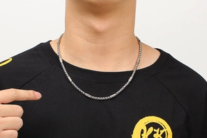 Detailed view of silver stainless steel cylinder link chain necklace on a model's neck