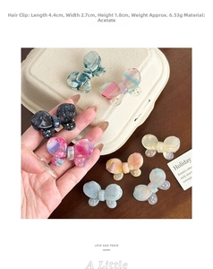 Detail of marble pattern acetate butterfly hair clips with gold label and rhinestone