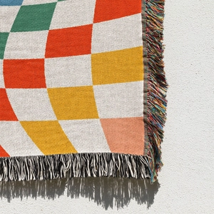 Detail of bohemian checkered woven blanket showing colorful tassels and cotton texture