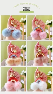 Hand holding colorful rainbow pompom keychains with woven cotton rope and golden bells